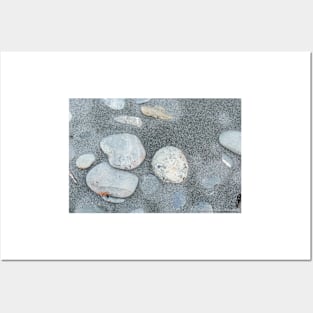 Stone scattered in sand on beach Posters and Art